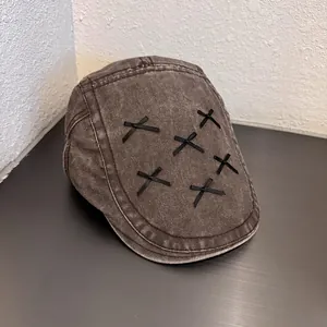 Detail of vintage washed denim flat cap with black ribbon cross stitching decorations