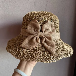 Detail of khaki straw hat featuring intricate hollow weaving and a large decorative bow
