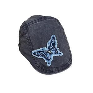 Vintage dark gray washed denim beret featuring a blue butterfly patch with distressed edges