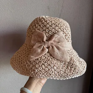 Close-up of khaki straw hat with hollow weave texture and large elegant bow detail