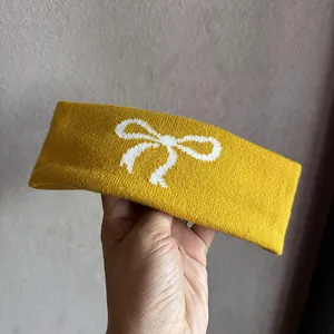 Details eines gelben Strick-Haarbandes mit weißem Schleifenmuster und Textur