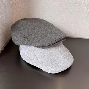 Classic newsboy flat caps in dark and light grey colors made of soft knit cotton fabric