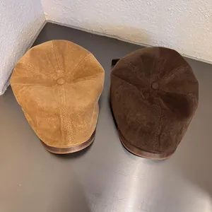 Detailed top view of khaki and dark brown corduroy ivy caps on a metallic surface