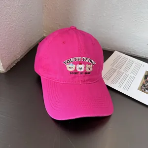 Detail van rozerode katoenen baseballpet met teddybeer borduursel en gebogen rand