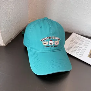 Detail van beertjes borduursel op cyaan katoenen baseballpet met lucky bear tekstprint