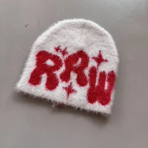 Nahaufnahme der weißen flauschigen Strickmütze mit roten RRW Buchstaben und Stern-Stickerei