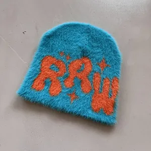 Detail der königsblauen Plüschmütze mit orangefarbenem RAW-Schriftzug und Mohair-Textur