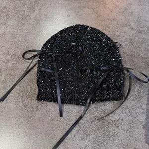 Schicke schwarze Pailletten-Strickmütze mit Satin-Schleifen auf grauem Hintergrund