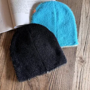 Detail von flauschigen Strickmützen aus Pelzimitat in Schwarz und Blau auf Holz