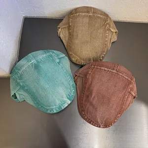 Dettaglio di tre coppole in denim lavato vintage nei colori verde, kaki e marrone