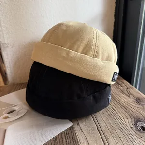 Harajuku retro brimless docker hats in beige and black colors on wooden table
