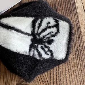 Detail der weichen Strickmütze aus Nerzimitat mit schwarz-weißem Schmetterlingsmuster