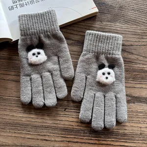Close-up of grey knitted gloves featuring a 3D plush panda patch on a wooden desk