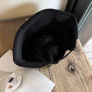 Detailed view of black docker hat interior construction with adjustable strap on wooden table