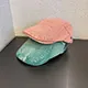 Dettaglio di cappelli stile newsboy rosa e verde acqua in cotone con cinturino regolabile