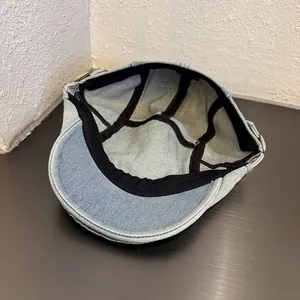 Dettaglio del berretto in denim blu chiaro con fascia interna e fibbia in metallo dorato