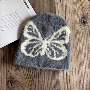 Nahaufnahme der grauen Webpelz-Strickmütze mit weißem Schmetterling-Jacquardmuster