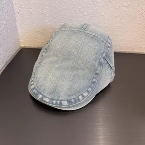 Dettaglio ravvicinato della trama in denim lavato azzurro e cuciture sulla coppola piatta
