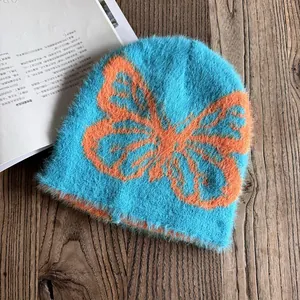 Detail der blauen Webpelz-Beanie mit großem orangefarbenem Schmetterlings-Jacquardmuster