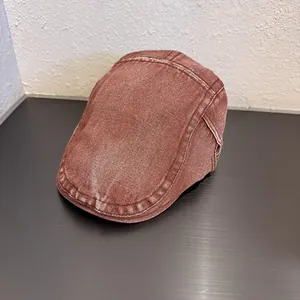 Dettaglio del berretto piatto in denim rosso mattone lavato con cuciture e trama