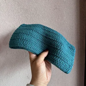 Nahaufnahme des petrolfarbenen Strickstirnbands mit grober Textur und Häkeldetails für Damen
