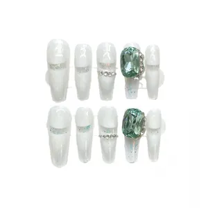 Uñas postizas blancas estilo francés con gema verde de lujo y detalles de purpurina plateada