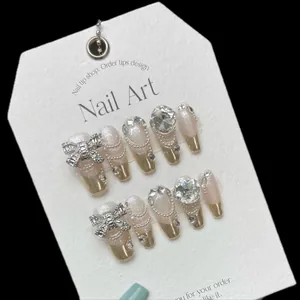 Handmade press-on nails with luxury silver bow, rhinestones, and pearls on ballet tips
