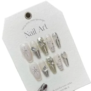 Faux ongles faits main blanc laiteux avec cœurs métalliques argentés et strass