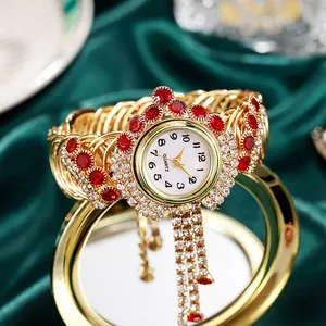 Macro detail of luxury gold quartz bracelet watch with red rhinestones and tassels