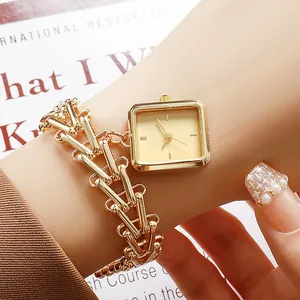 Detail of luxury gold square watch with unique V-shaped chain strap on a wrist