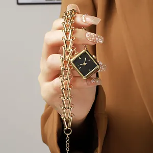 Detail of square black dial watch with chunky gold chain strap on a camel suit