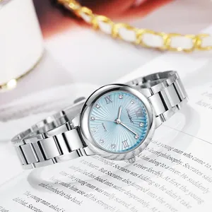 Macro shot of silver stainless steel watch with light blue dial and sparkling crystal indices