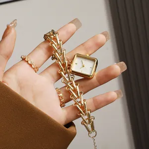 Detail showing square gold watch dial with wheat-inspired bamboo chain bracelet strap