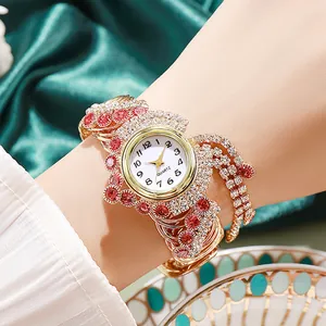 Detail of luxury gold quartz watch featuring red gems and rhinestone tassel on wrist