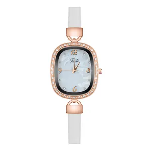 Detail of oval rose gold watch case with crystal bezel and narrow white leather strap