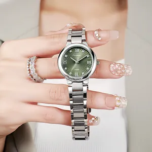 Detail of luxury green dial watch with crystal markers on woman's wrist with jewelry