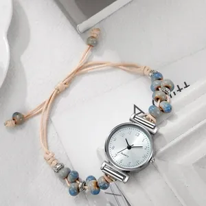 Detalle de correa de reloj con cuentas de mármol y dijes de metal plateado estilo retro
