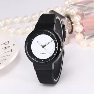 Minimalist black silicone quartz watch on white plate with elegant pearls and perfume