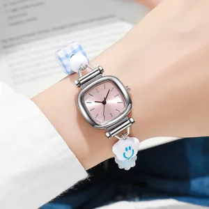 Detail of square silver watch with pink sunray dial and beaded cloud charm bracelet