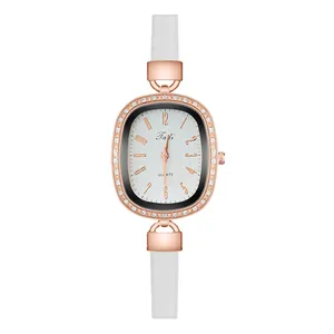 Detail of elegant oval rose gold watch with sparkling diamonds and white slim leather strap