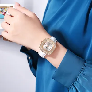 Close-up of a women's square rhinestone watch with white leather strap and floral cup