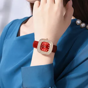 Close-up of a women's rose gold square watch with red leather strap and crystal bezel