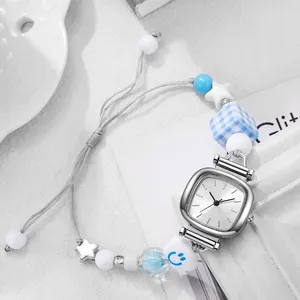 Close-up of ceramic beaded woven strap watch with square silver dial and star charms
