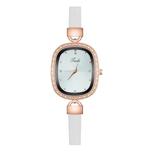 Close-up of elegant rose gold oval watch case with white crystals and white leather strap