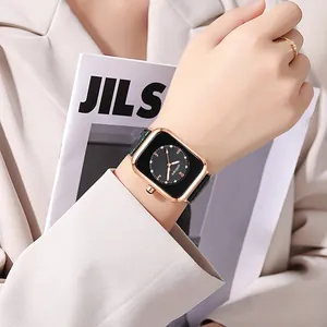 Detail of a square rose gold watch with black dial and leather strap worn on wrist