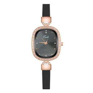 Detail of rose gold oval watch with crystal bezel and slim black leather strap