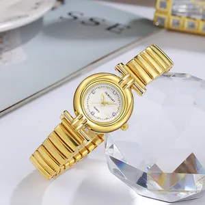 Détail macro d'une montre à quartz dorée pour femme avec cadran texturé et bracelet à maillons