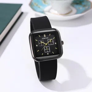 Detailed close-up of a black square watch dial with gold markers on a green notebook