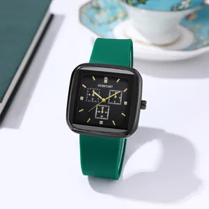 Detail of square black dial with gold hands and flexible green silicone watch strap