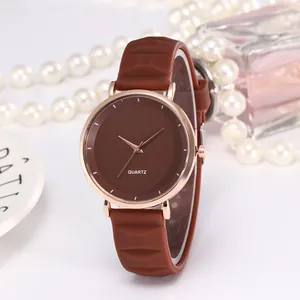 Détail de montre quartz or rose avec bracelet en silicone marron et accessoire perle